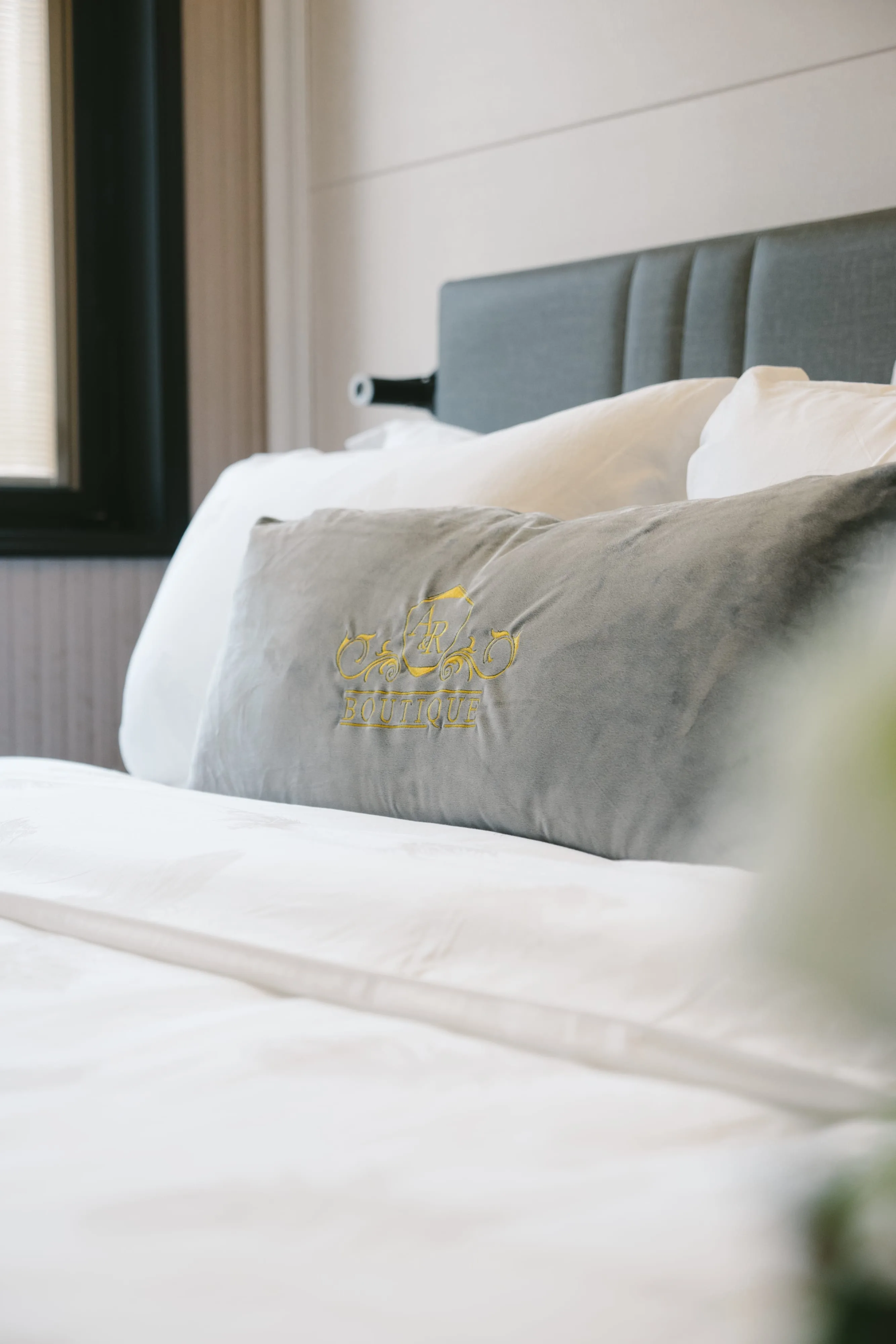 Deluxe Queen bed with A&R Boutique logo cushion by window, Cheras